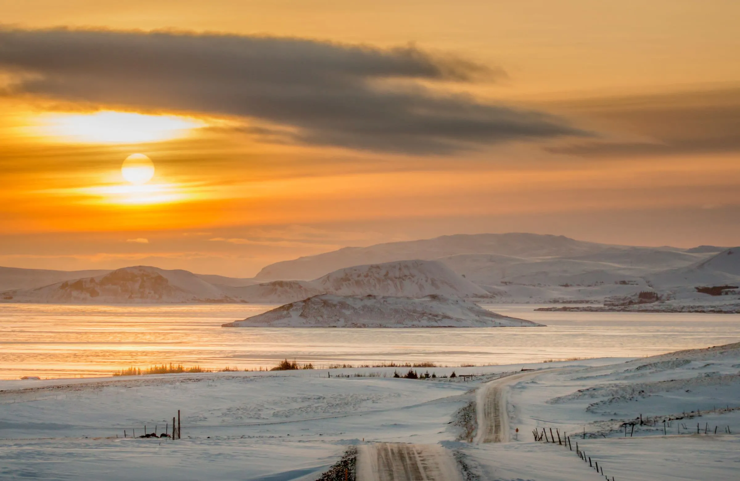 A road running into low sun across an empty Icelandic plain