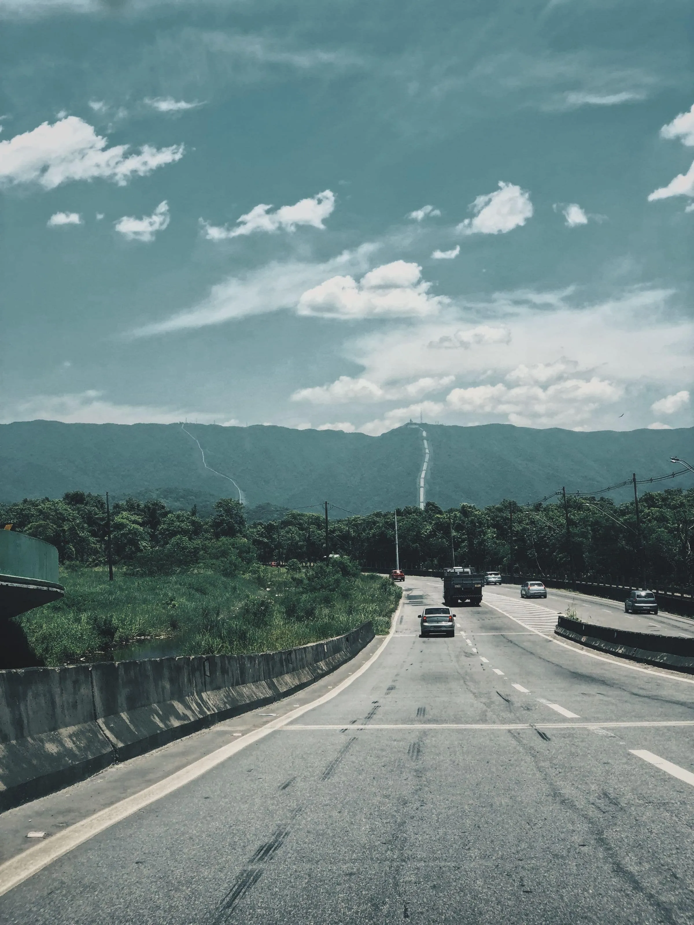 A straight empty road running towards distant hills