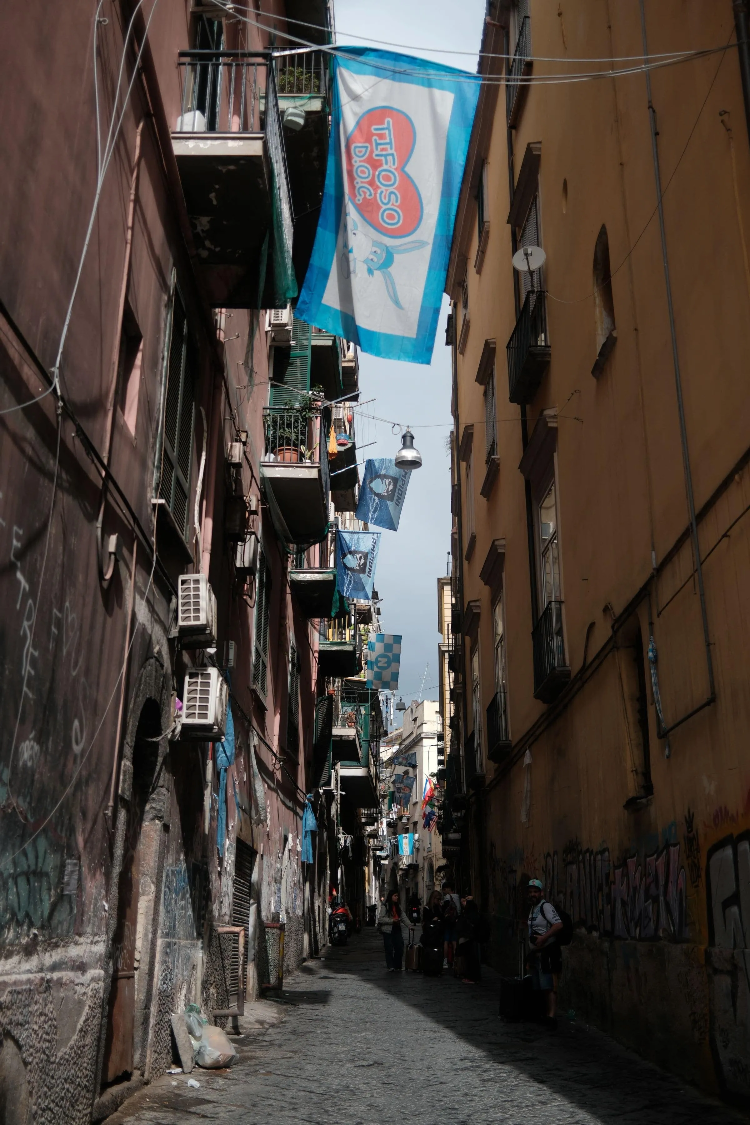 A narrow Naples alley with washing hung between tall shuttered buildings