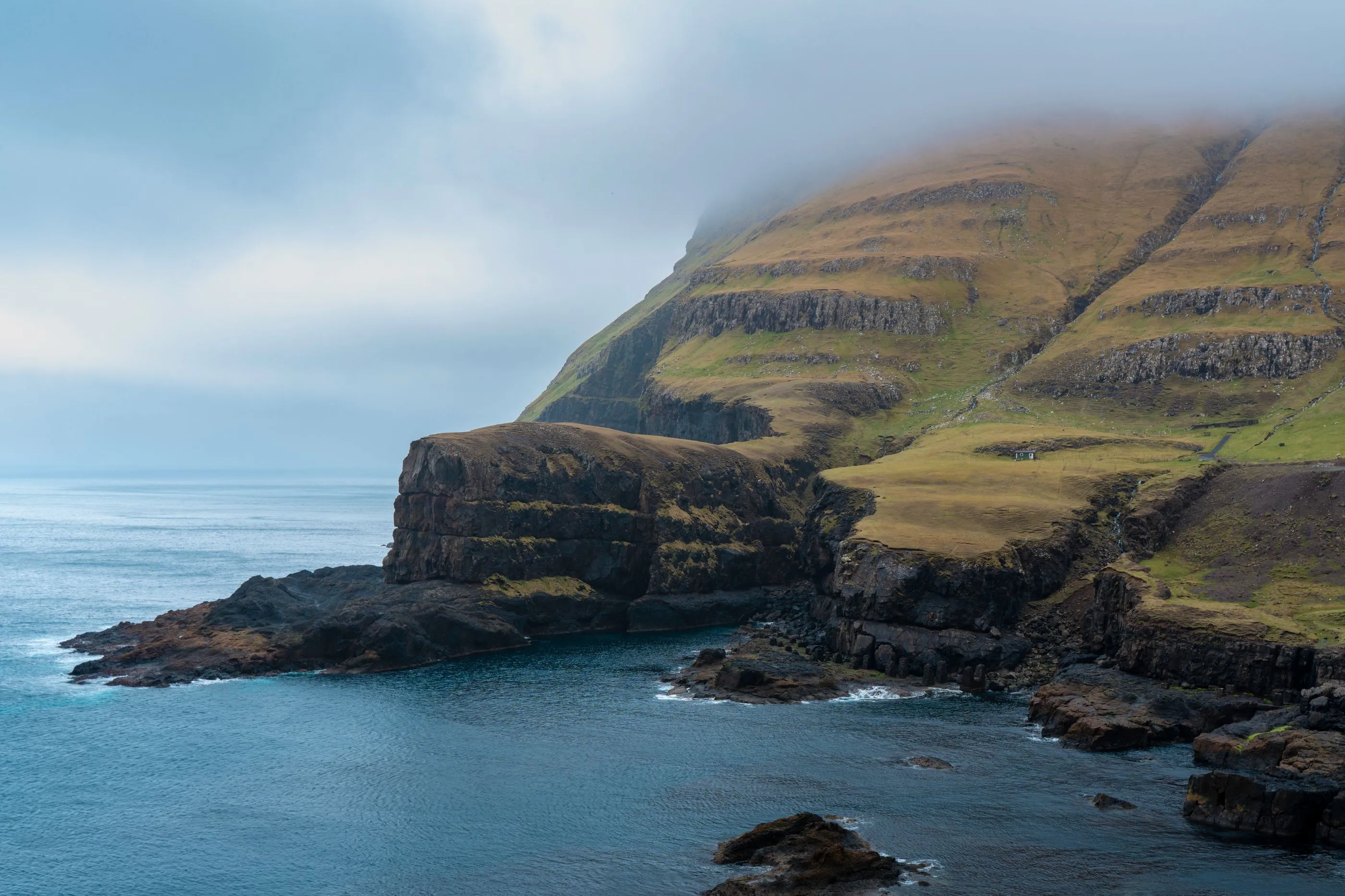 Mist coming off the sea against the steep green cliffs of the Faroes