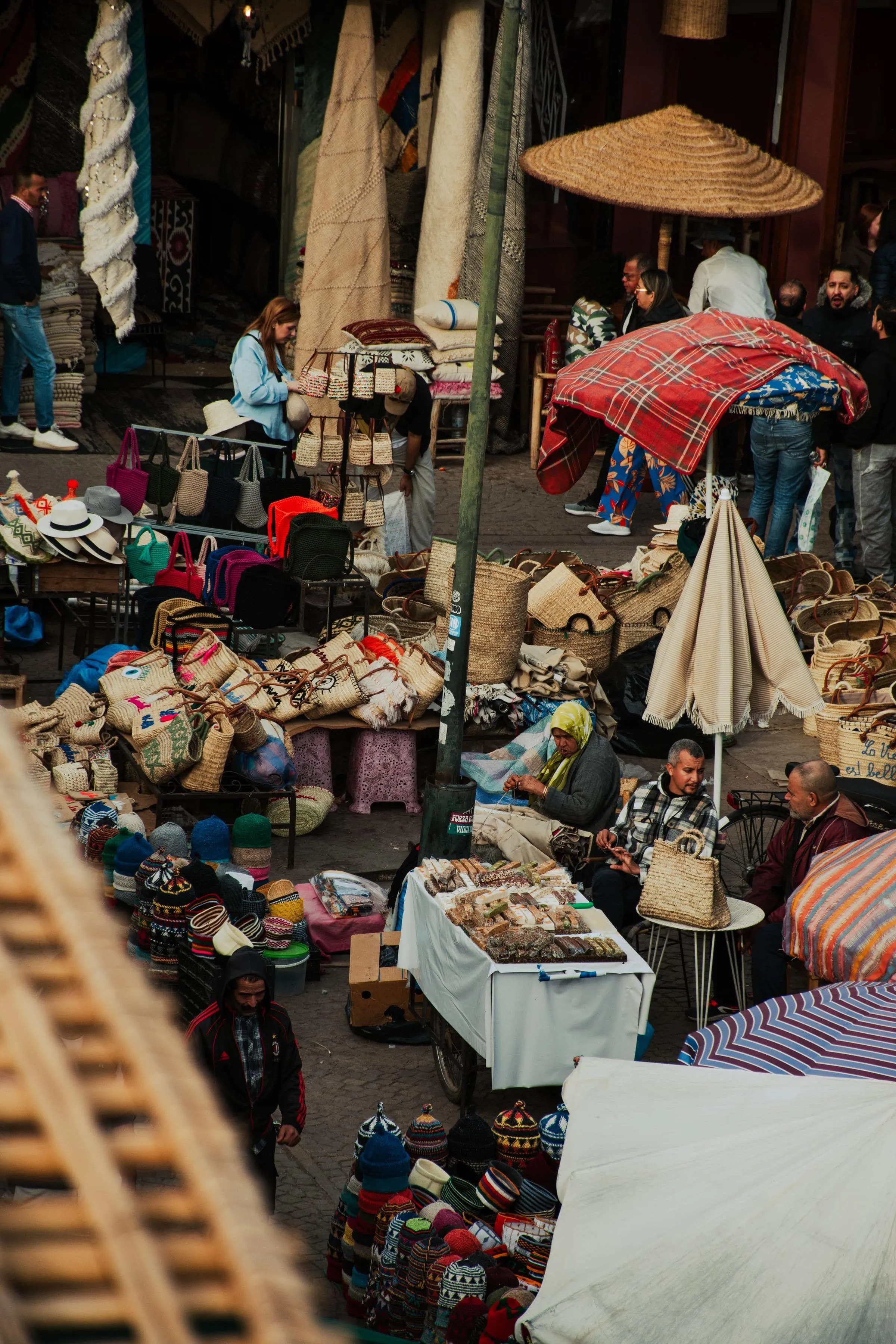 A busy market stall with rugs, baskets and an umbrella overhead