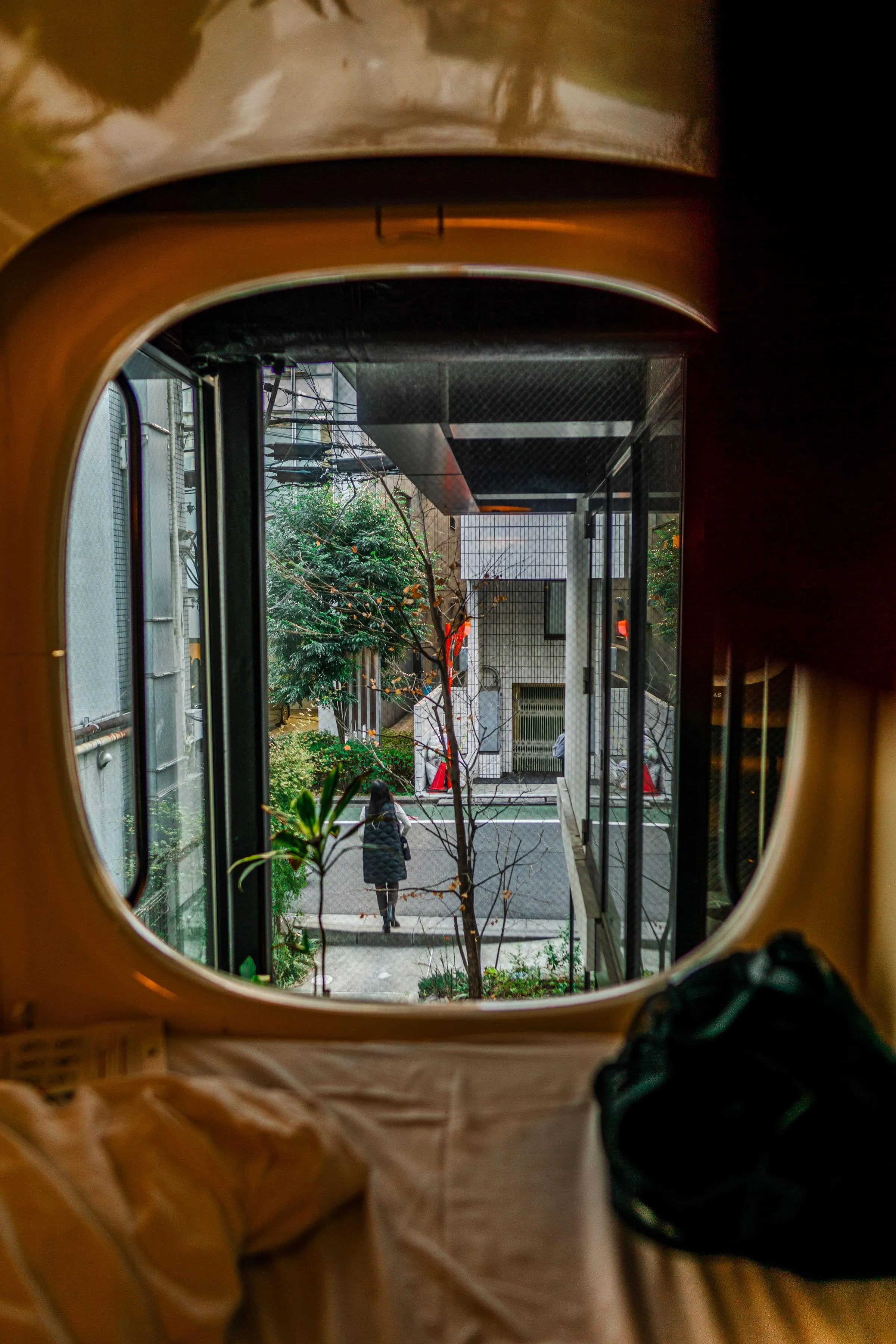 A round porthole window looking out onto a street from a dim room