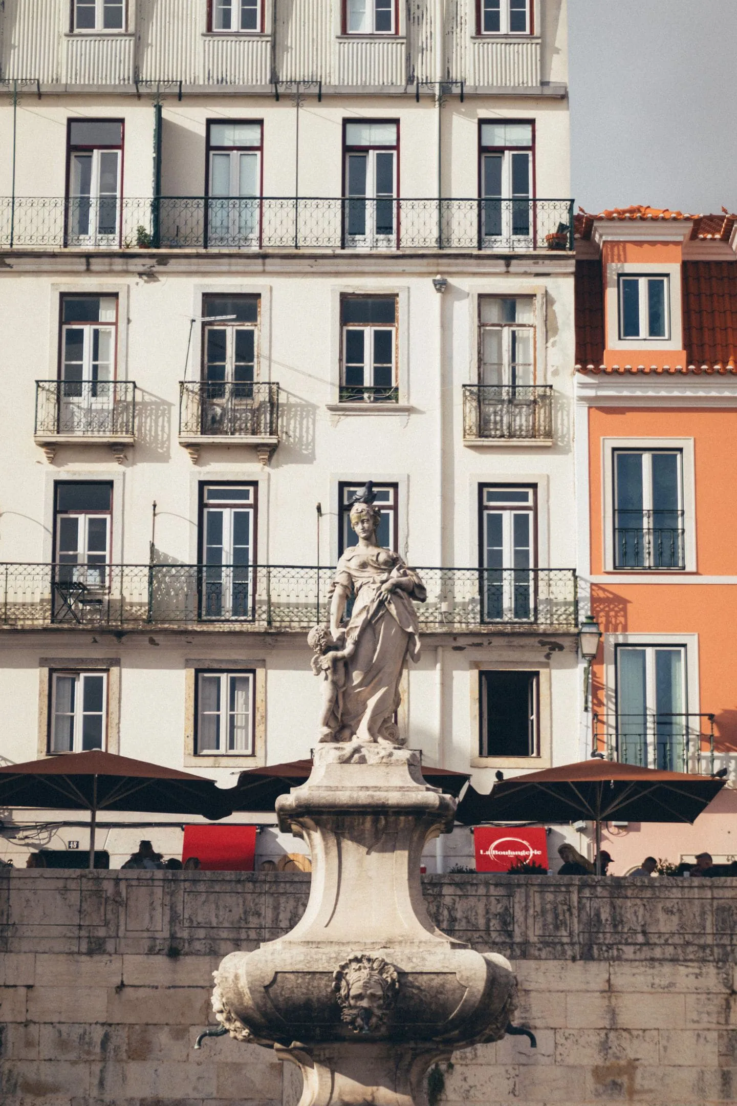 A statue on a plinth in front of tiled Lisbon townhouses