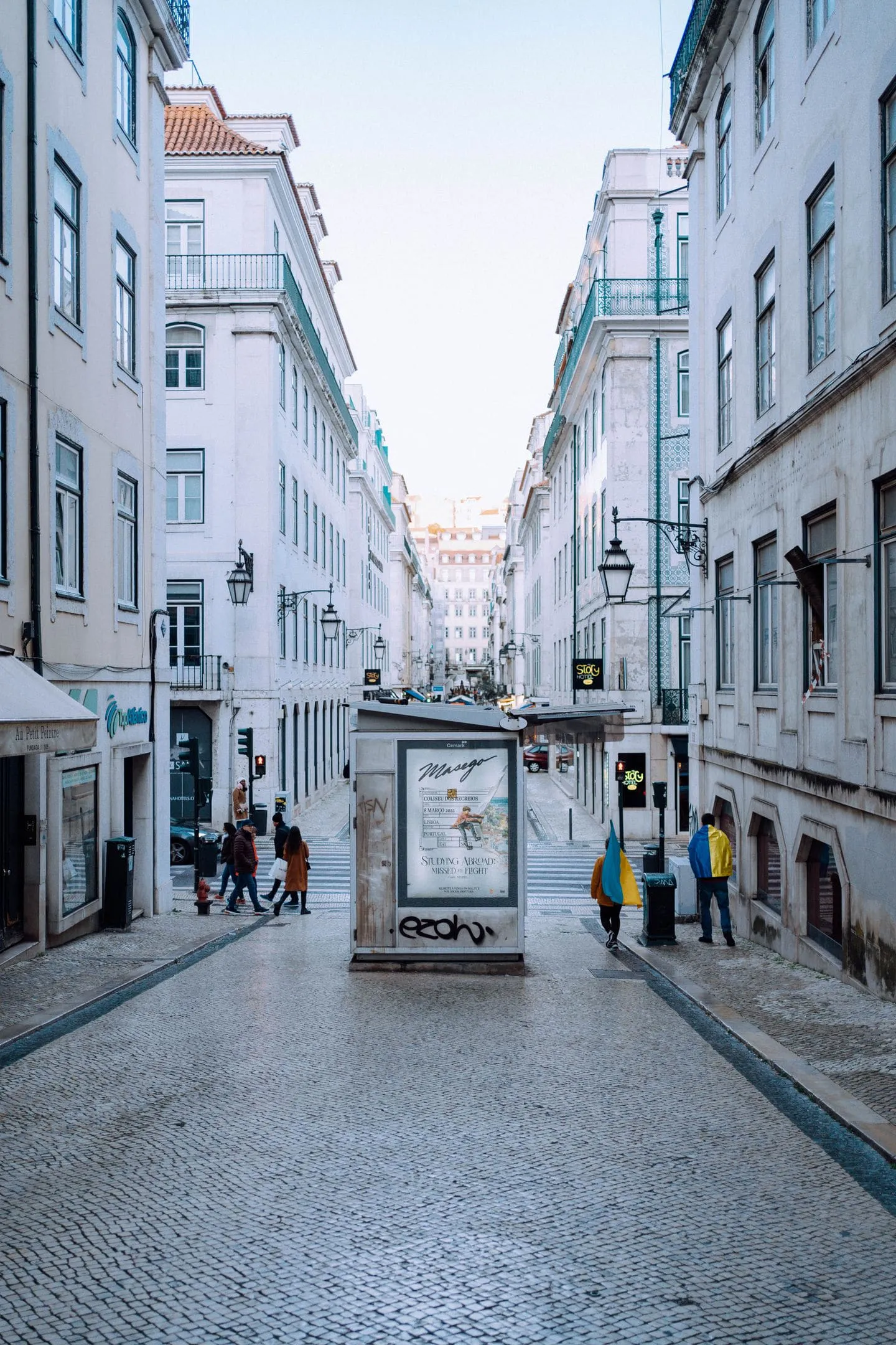 A pedestrian street in central Lisbon lined with shops and street lamps