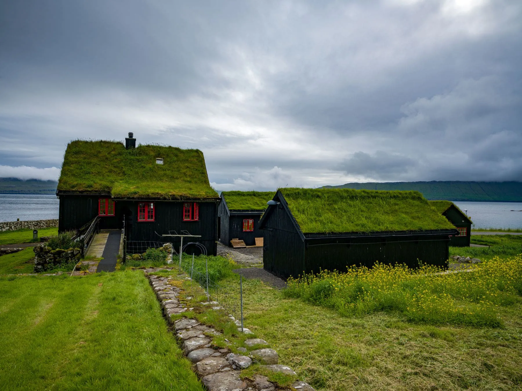 Turf-roofed black timber houses on a green headland by the sea