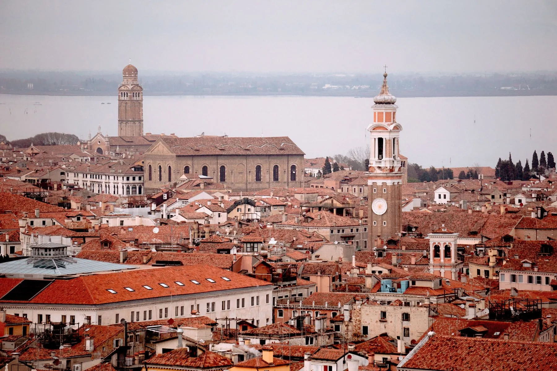 Venetian rooftops and a campanile above the lagoon in flat light