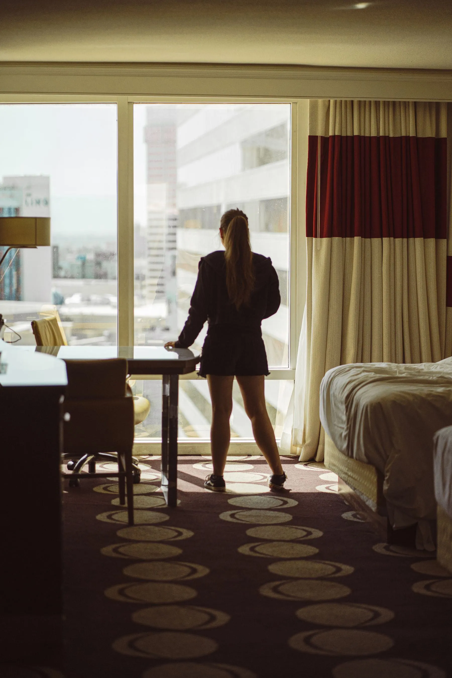 A hotel room with an unmade bed and morning light through a window