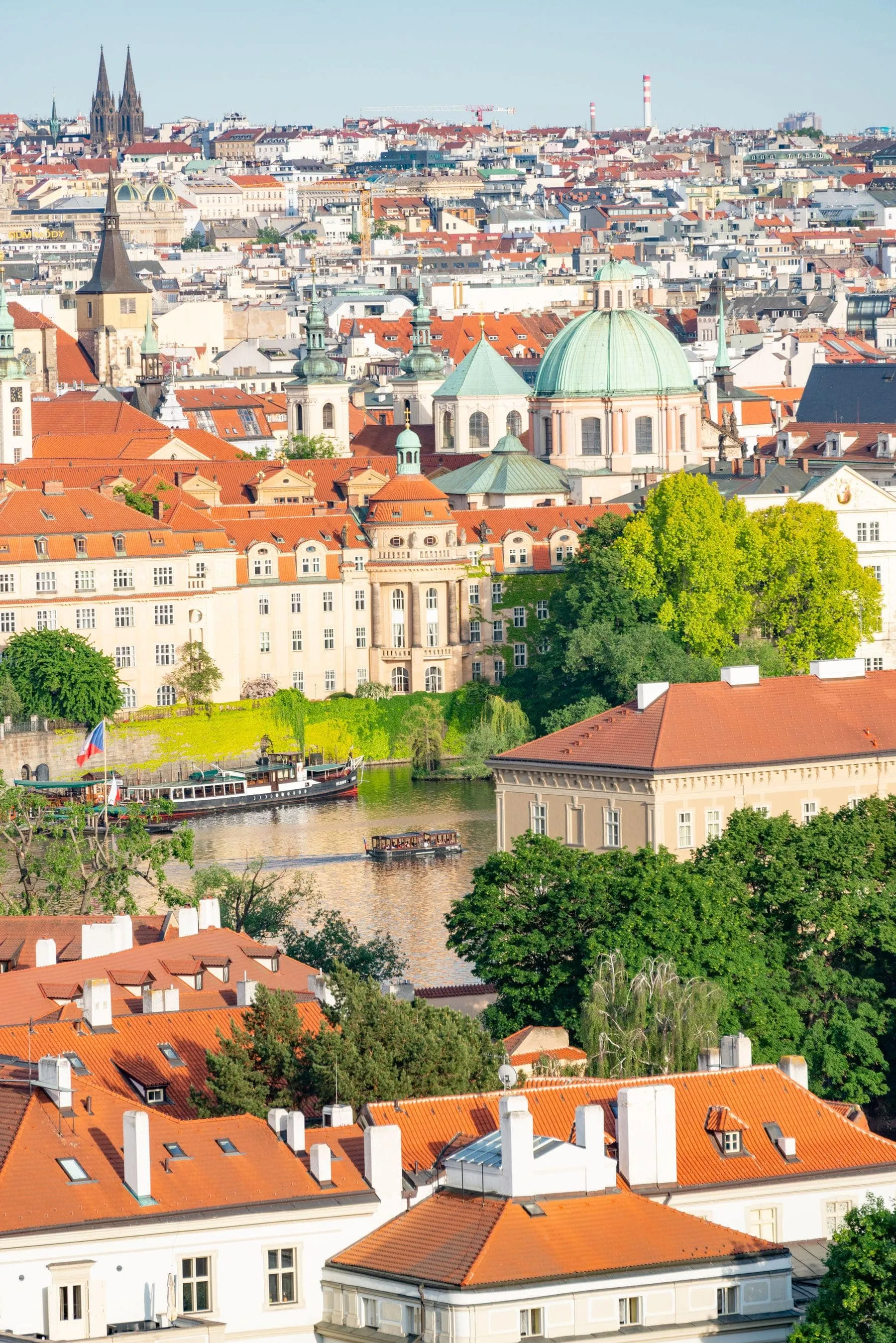 Prague rooftops and church towers above the river, seen from the castle side