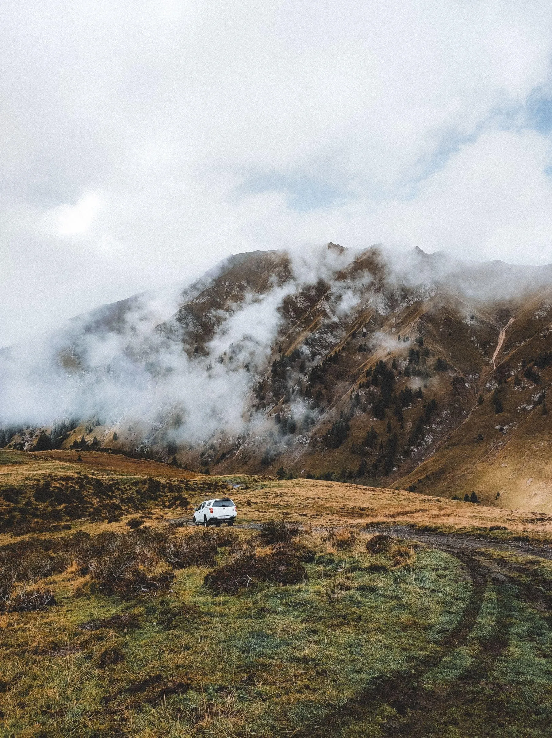 A wet mountain road disappearing into low cloud