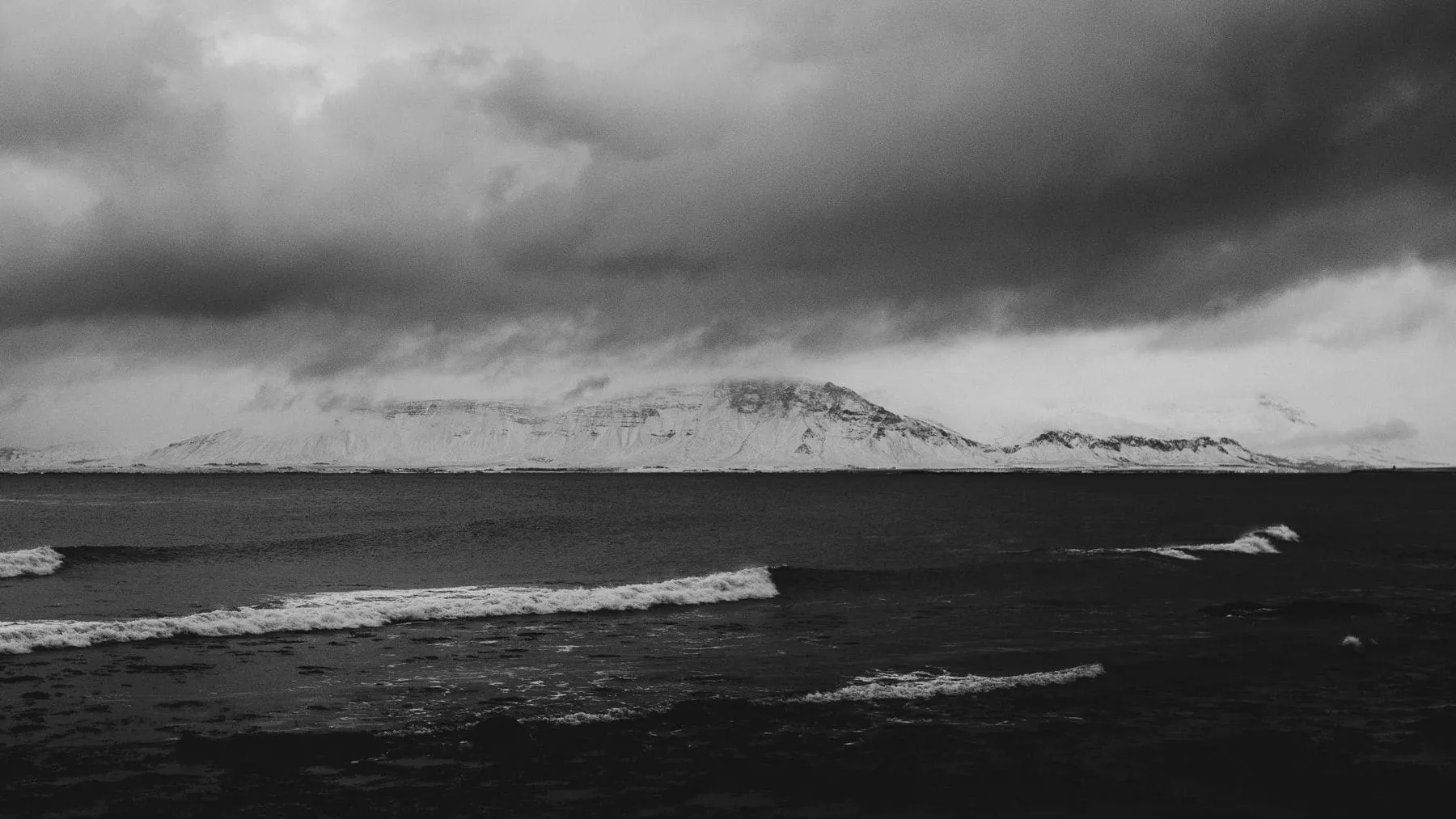 A black and white photograph of a rough sea against a low grey horizon